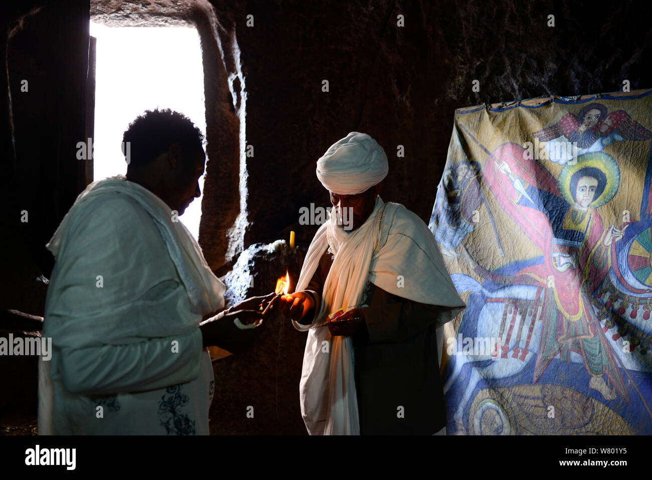 Fervent chrétien traditionnel de robess bougie d'éclairage en face de pari Danaghel (partie de la nord-ouest de groupe d'églises à Lalibela). UNESCO World Heritage Site. Lalibela. L'Éthiopie, décembre 2014. Banque D'Images