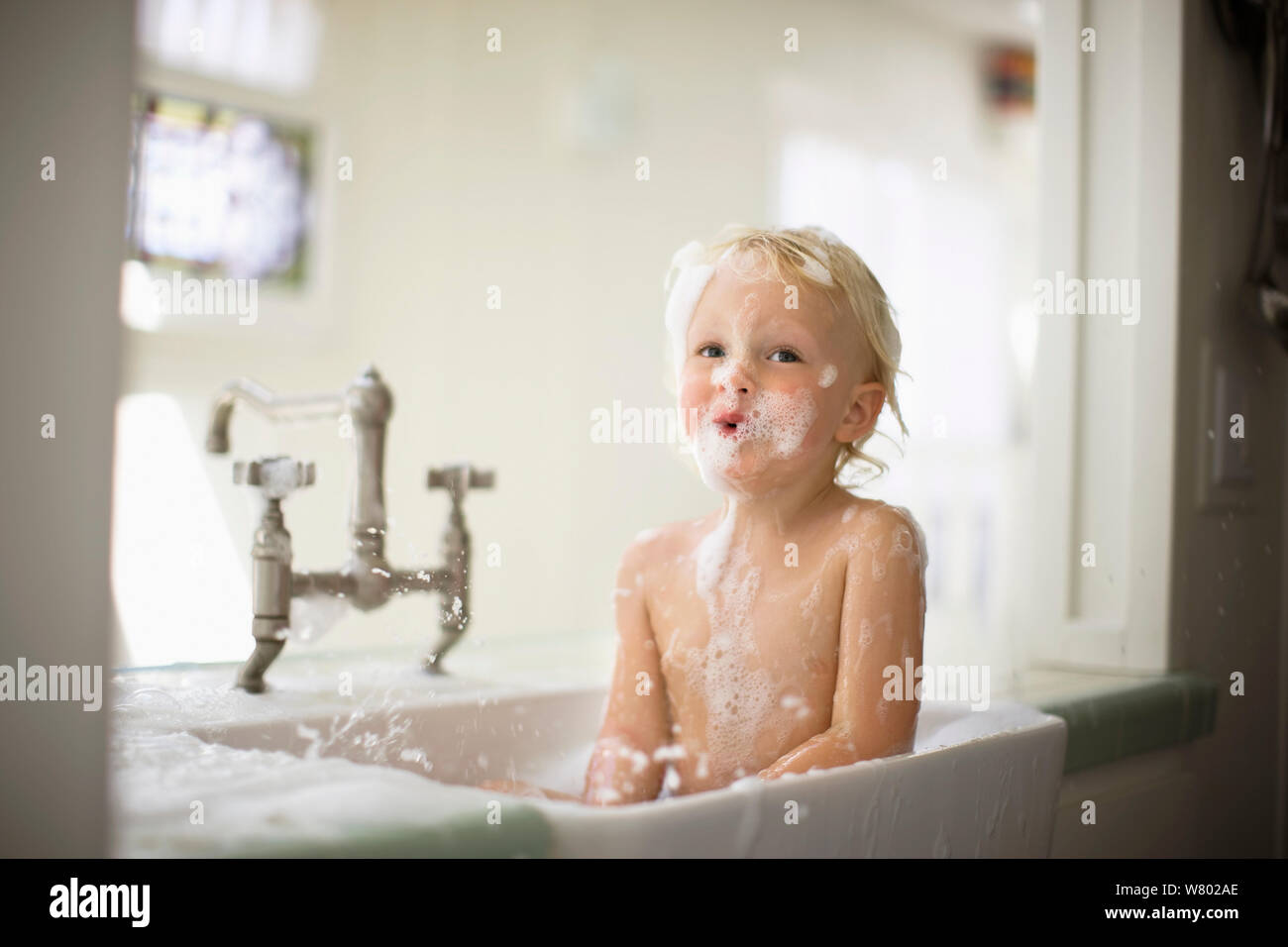 Portrait d'un enfant en s'amusant tout en prenant un bain moussant. Banque D'Images