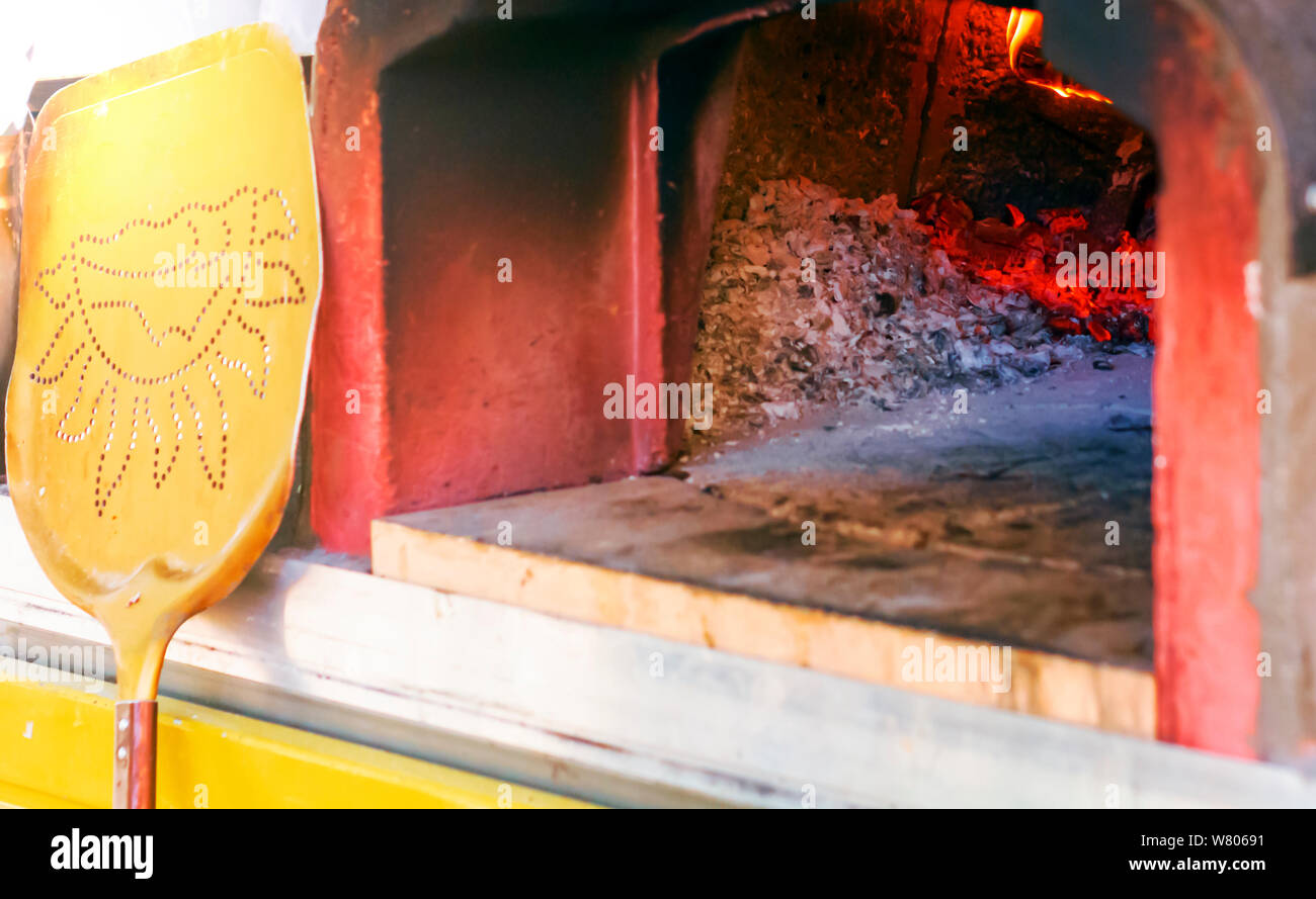 Four à bois pour la cuisson des pizzas avec cendres, la combustion des braises et à l'incendie. Appuyé contre le four une pelle pour prendre les pizzas du four une fois Banque D'Images