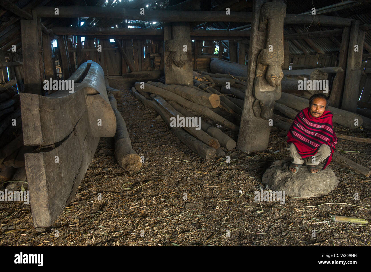 Naga Konyak man crouching par Hongphoi Village log drum. Mon district. Le Nagaland, dans le Nord Est de l'Inde, octobre 2014. Banque D'Images