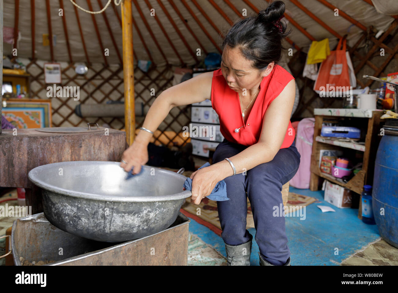 Femme mongole nettoyer ses casseroles dans son ger. Banque D'Images