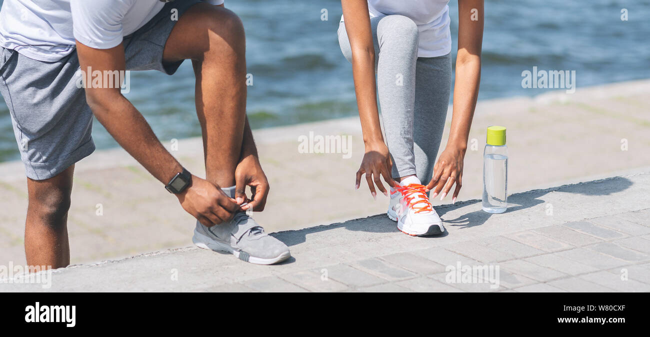 Couple Afro Chaussures laçage à côté de River Embankment, Cropped Banque D'Images