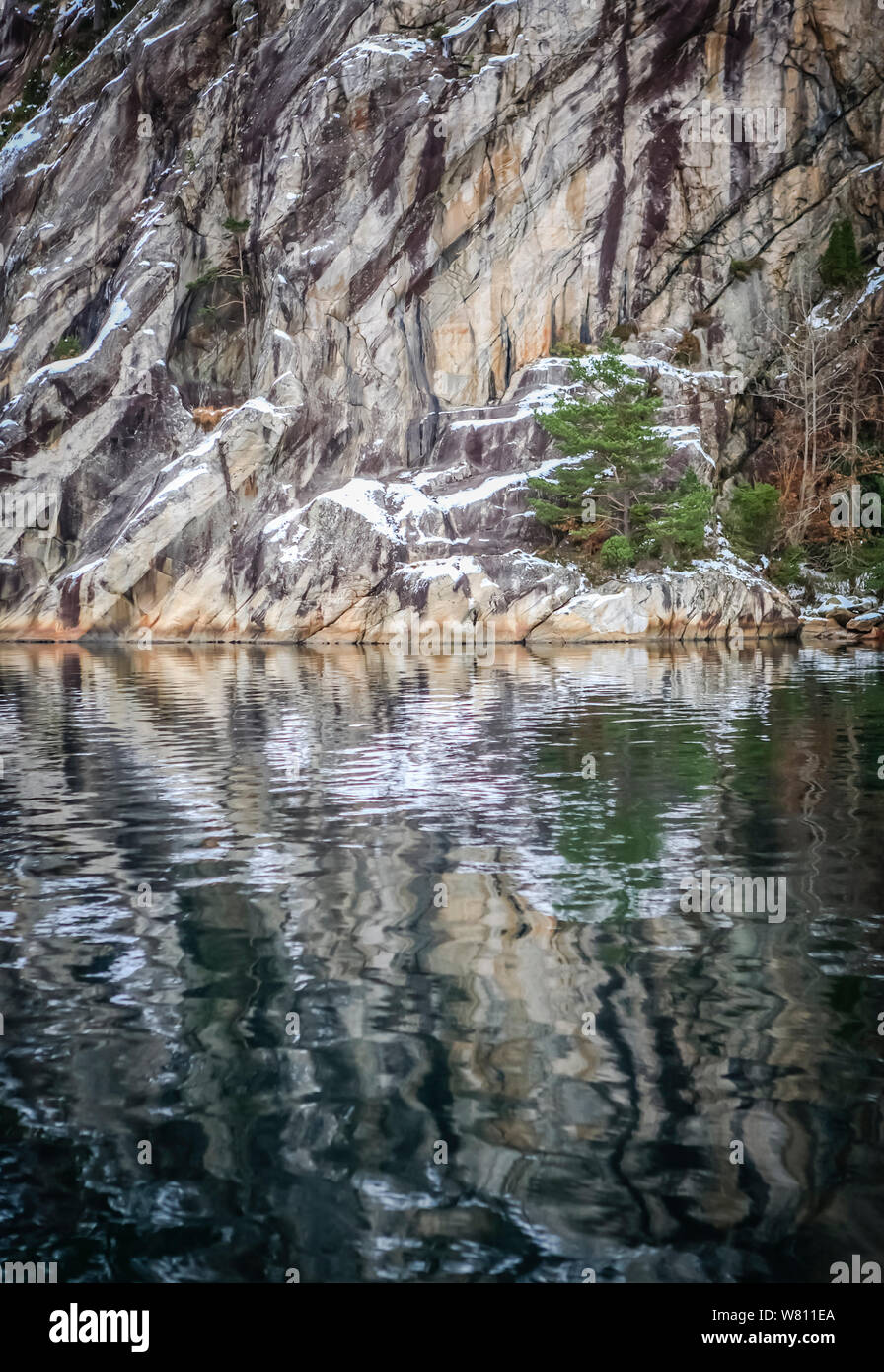 Voir à travers l'eau d'un fjord norvégien avec une fine couche de neige sur les collines Banque D'Images