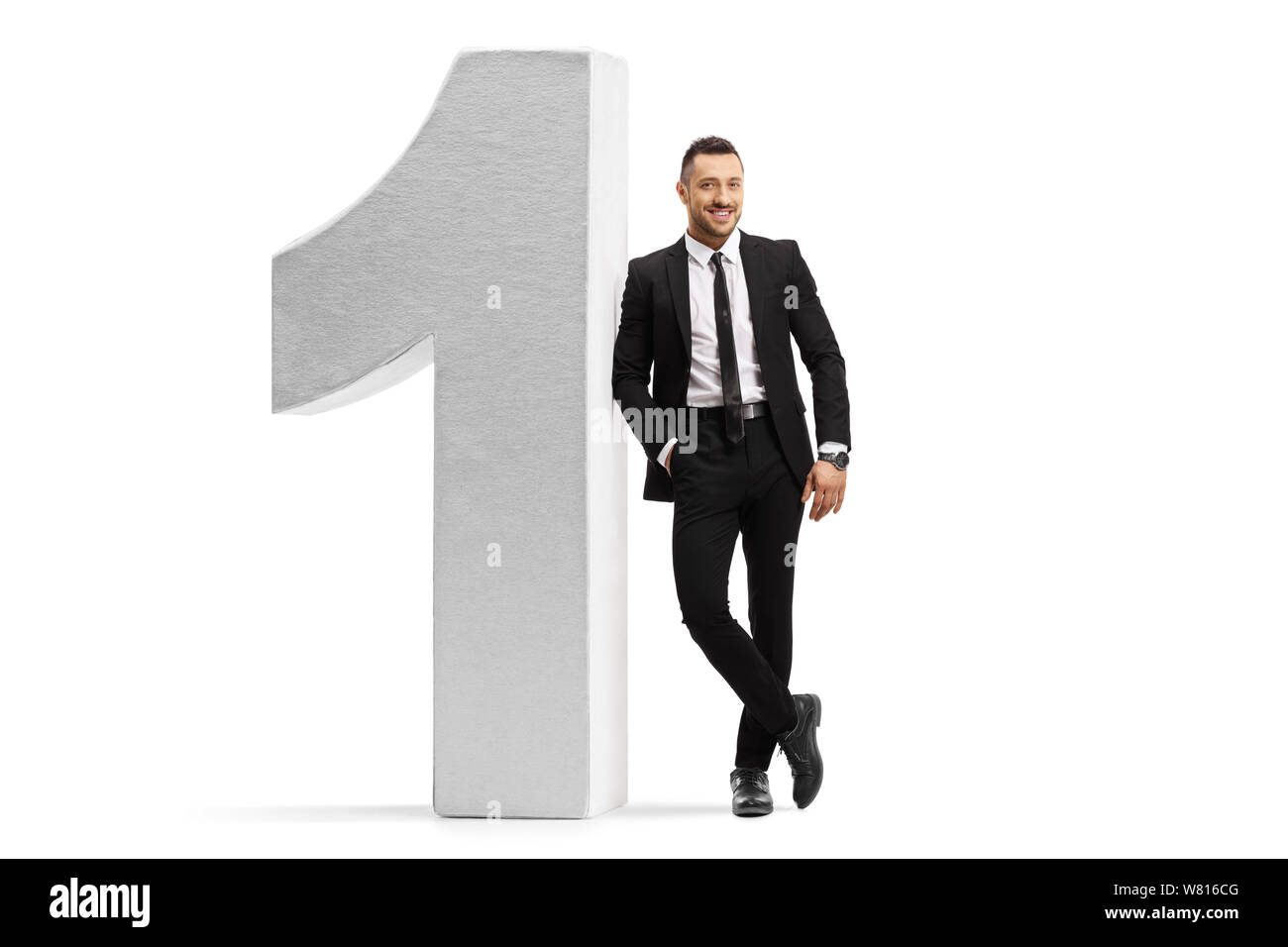 Portrait d'un homme dans un costume noir et une cravate s'appuyant sur un nombre isolé sur fond blanc Banque D'Images