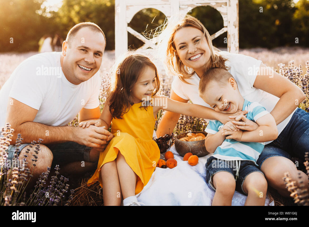 Portrait d'une belle famille caucasienne assis dans un champ de lavande faire un pique-nique à la caméra en embrassant et en riant et s'amusant contre su Banque D'Images