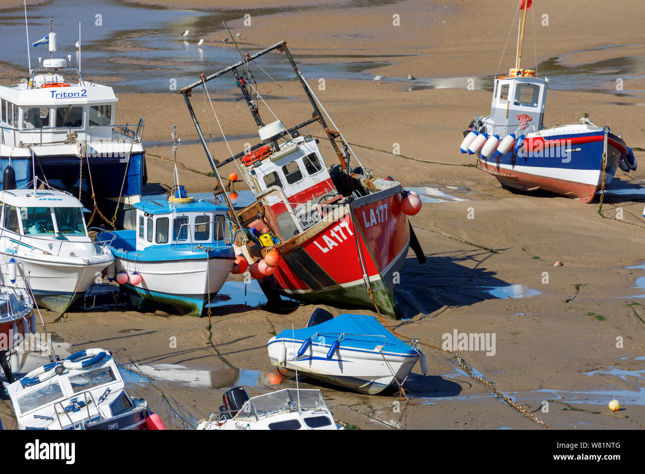 Les bateaux de pêche s'échouer à marée basse dans le port de Tenby, une ville balnéaire fortifiée dans la région de Pembrokeshire, Pays de Galles du sud sur la côte ouest de la baie de Carmarthen Banque D'Images