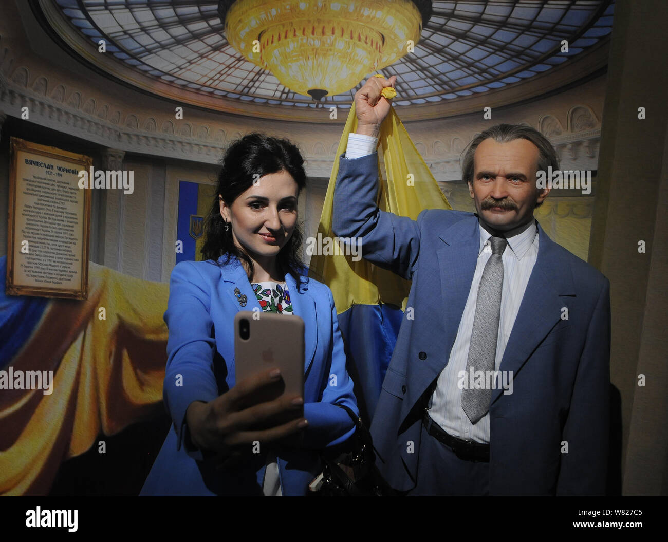 Une femme prend un avec l'homme politique ukrainien selfies, dissident, héros de l'Ukraine Vyacheslav Chernovol sur l'arrière-plan pendant l'ouverture de la musée innovant, la formation de la nation ukrainienne, à Kiev.Le musée a 25 compositions de tracé, où chaque installation est accompagnée d'un contenu audio et vidéo interactif, d'odeurs, de dispositifs de réalité virtuelle, qui permet au visiteur de sentir l'atmosphère de l'époque dans laquelle il est. Aussi dans le musée 'La Formation de la nation ukrainienne' vous pouvez voir 100 chiffres d'éminents ukrainiens de la Princesse Olga aux personnalités de Banque D'Images