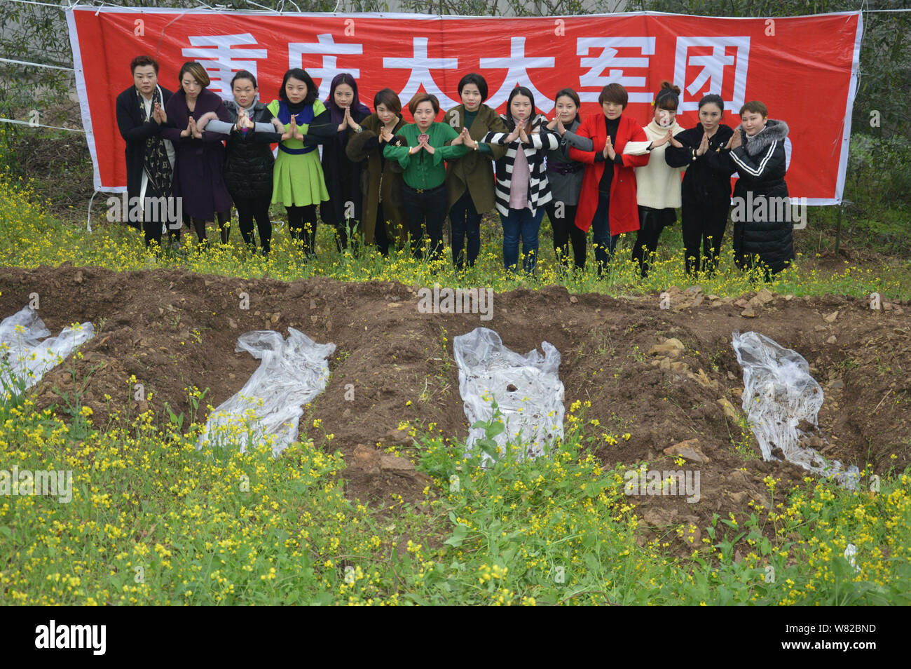 Femmes chinoises méditer avec leurs mains en une prière avant de se positionner dans des "tombes" au cours d'un rituel peu commun pour aider à faire face à leur divorcés Banque D'Images