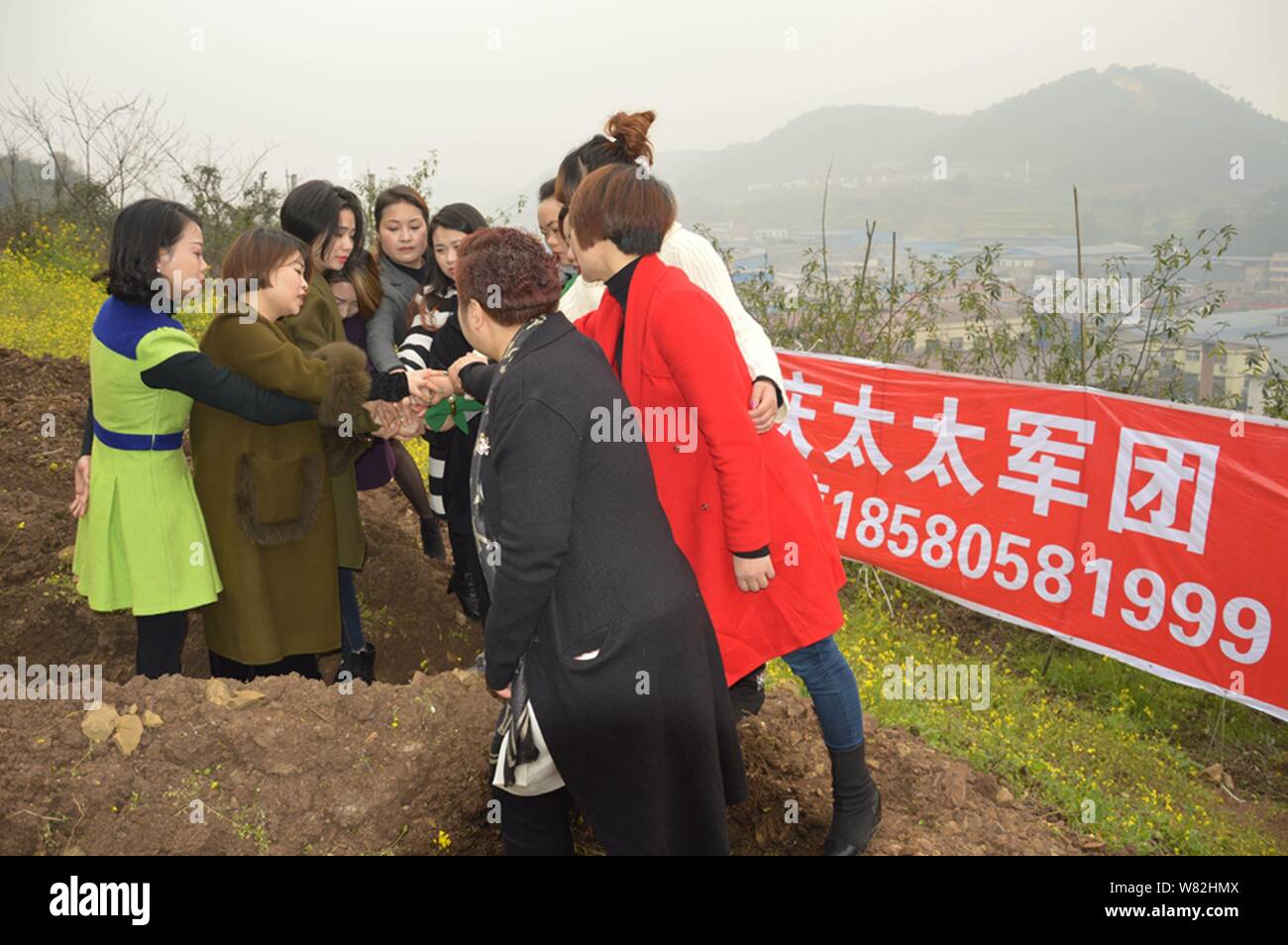 Les femmes chinoises s'applaudir après être resté dans des "tombes" au cours d'un rituel peu commun pour aider les divorcés à faire face à leur rupture du mariage dans l'out Banque D'Images