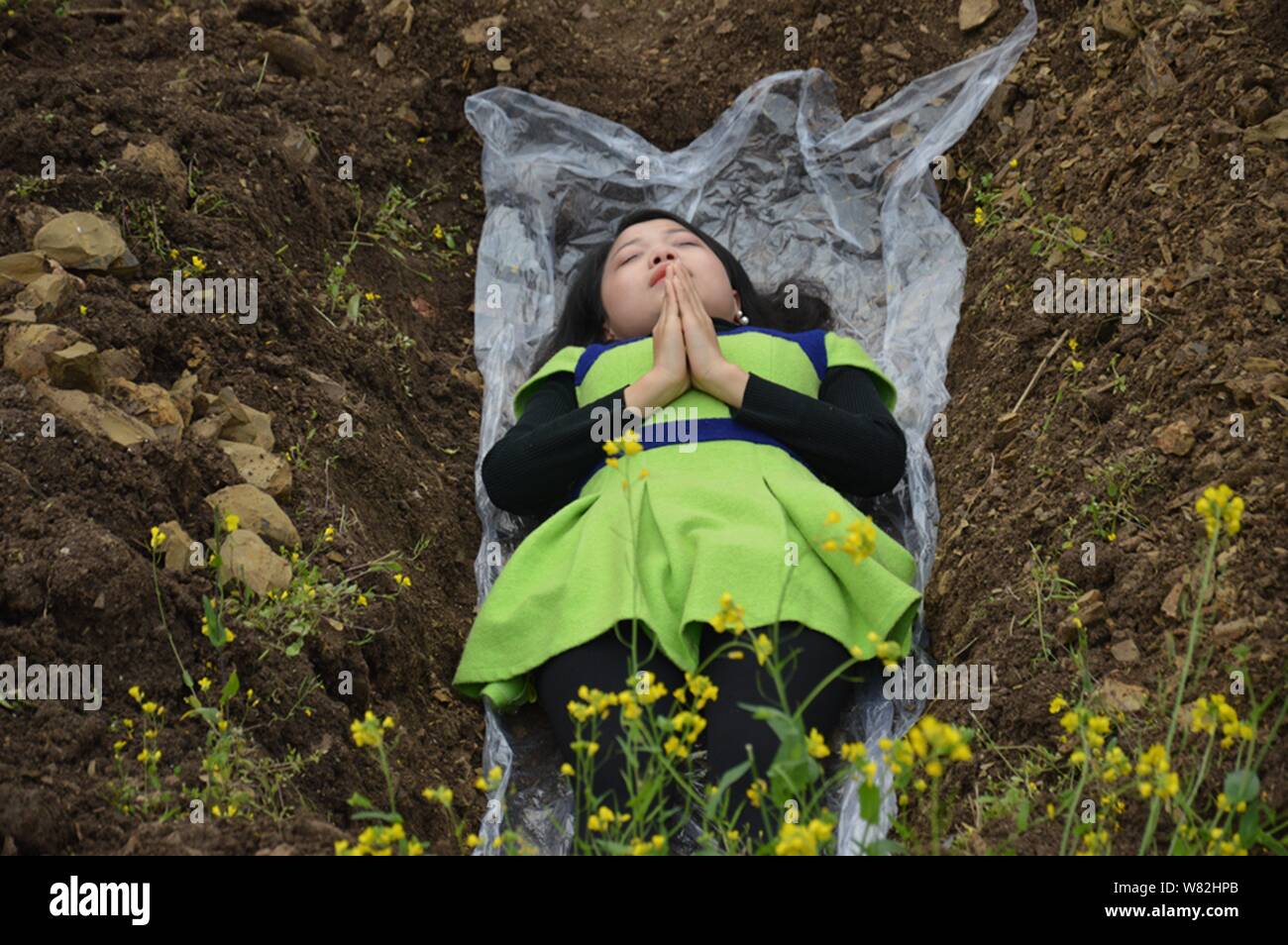 Une femme chinoise se trouve dans un tombeau 'terre' dans la loi de 'cimetière' méditation au cours d'un rituel peu commun pour aider à faire face à leur mariage divorcés ne parviennent pas Banque D'Images