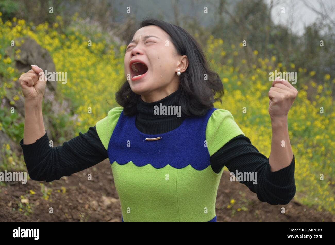 Une femme chinoise pleure avec ses poings en l'air au cours d'un rituel peu commun pour aider les divorcés à faire face à leur échec du mariage dans la périphérie de Chongq Banque D'Images