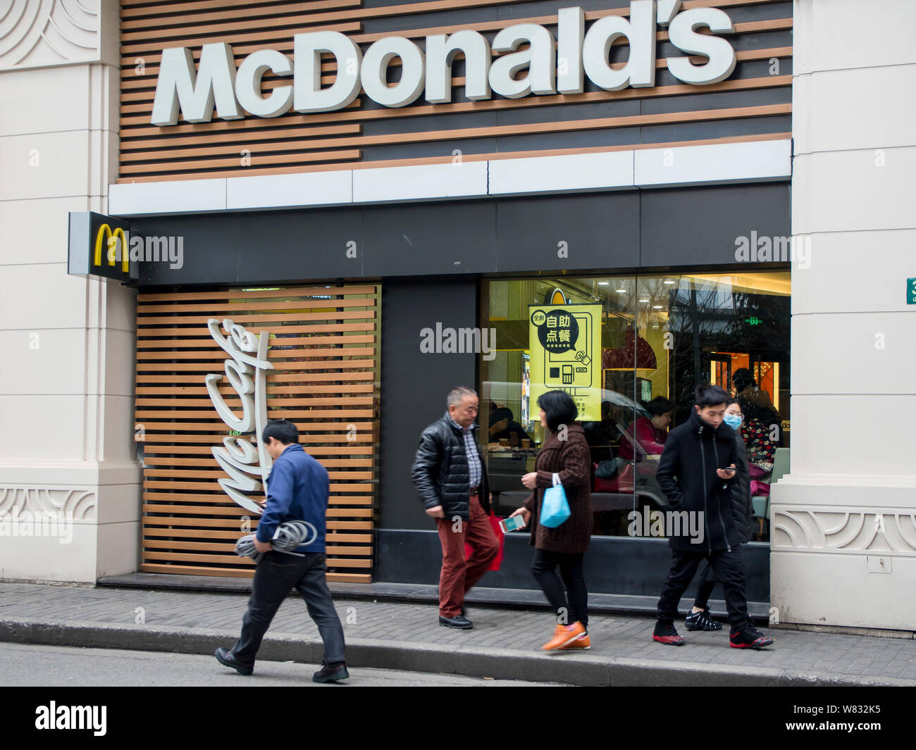 Les piétons passent devant un restaurant de fast-food McDonald's à Shanghai, Chine, le 9 janvier 2017. McDonald's corp a accepté de vendre l'essentiel de son Chi Banque D'Images