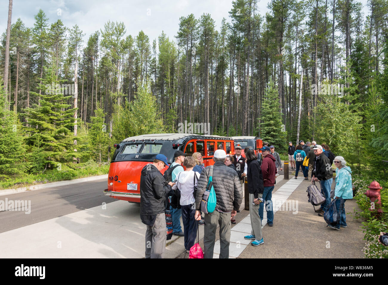 Les visiteurs du parc national des Glaciers dans l'attente de l'Red Bus Tour à l'arrêt de bus du centre d'Apgar Banque D'Images