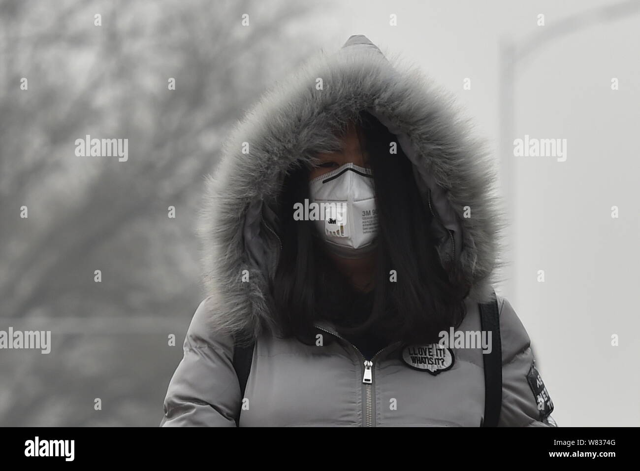 Un piéton portant un masque contre la pollution de l'air promenades sur la rue dans le smog lourde à Beijing, Chine, 20 décembre 2016. Le nord de la Chine était shr Banque D'Images