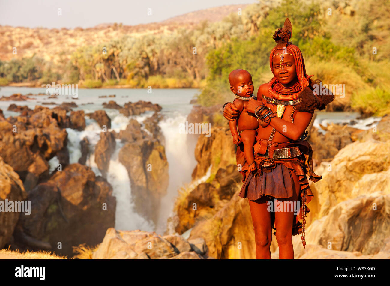 Femme Himba avec bébé sur les Chutes Epupa. Himbas sont normalement trouvés près des chutes où ils peuvent gagner de l'argent se faisant passer pour des touristes, la Namibie Epupa Banque D'Images