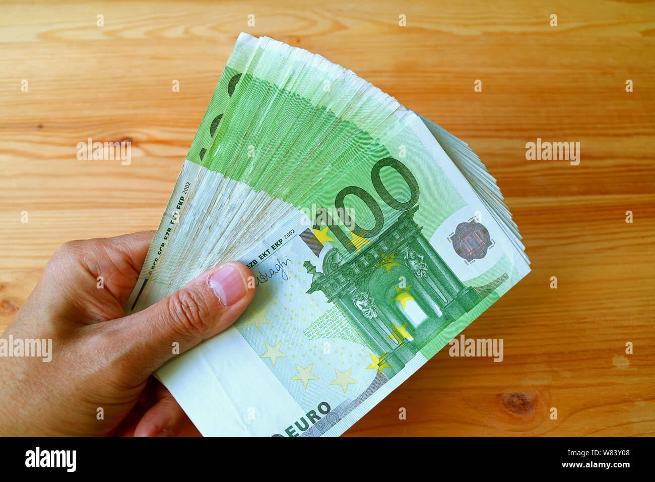 Bande de 100 billets dans la main de l'homme avec table en bois dans la toile Banque D'Images