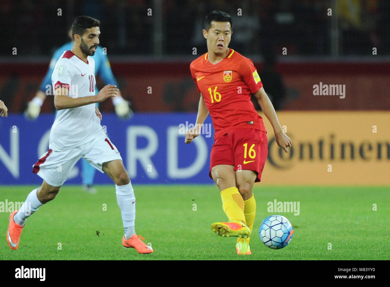 Huang Bowen de Chine, droite, passe le ballon contre un joueur du Qatar dans leur groupe une ronde 3 match pendant la Coupe du Monde 2018 éliminatoires asiatiques Banque D'Images