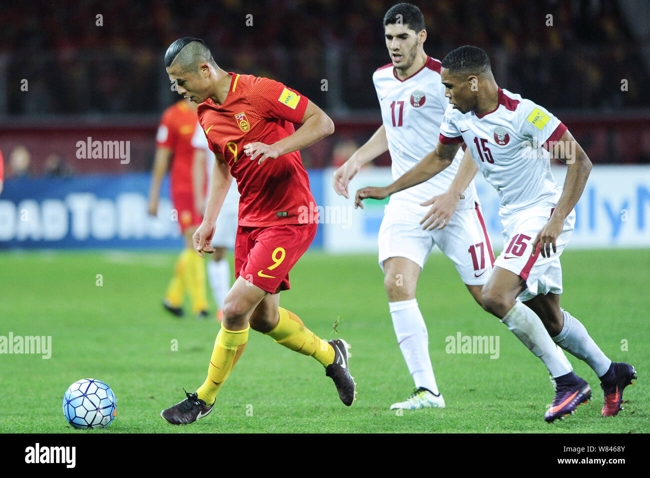 M. Yuning Zhang de Chine, à gauche, les joueurs du Qatar dans leur groupe une ronde 3 match pendant la Coupe du Monde FIFA 2018 qualificatifs asiatique à Kunming cit Banque D'Images