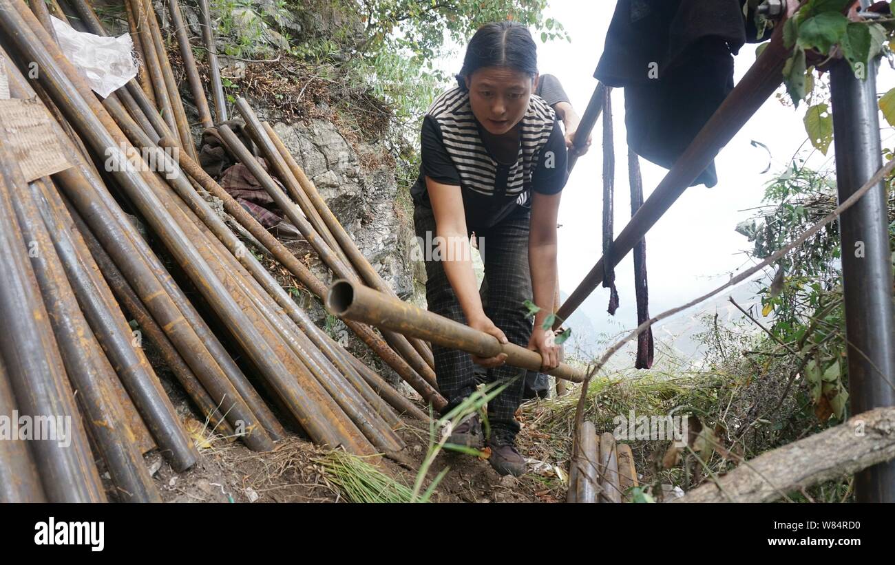 Un villageois chinois met en tuyaux d'acier qui sert à la construction d'une échelle d'acier sur la falaise d'une montagne dans Atulieer village, Ürümqi Yi Auton Banque D'Images