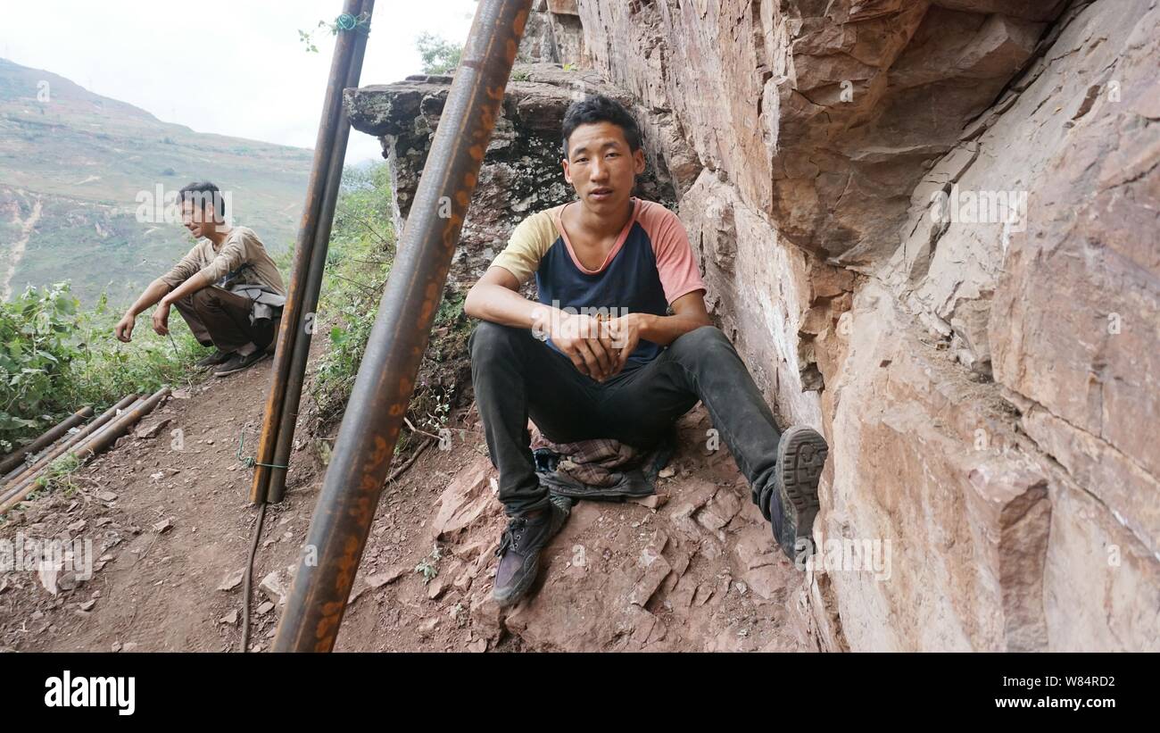 Des villageois chinois reste à côté de tuyaux d'acier qui sert à la construction d'une échelle d'acier sur la falaise d'une montagne dans Atulieer village, Ürümqi Yi Autonom Banque D'Images