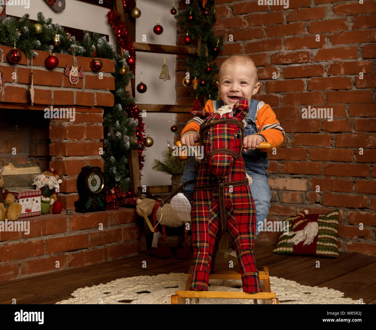 Petit bébé garçon sur le cheval à bascule, habillé en jeans et pull. Décorations de Noël ou Nouvel An Banque D'Images