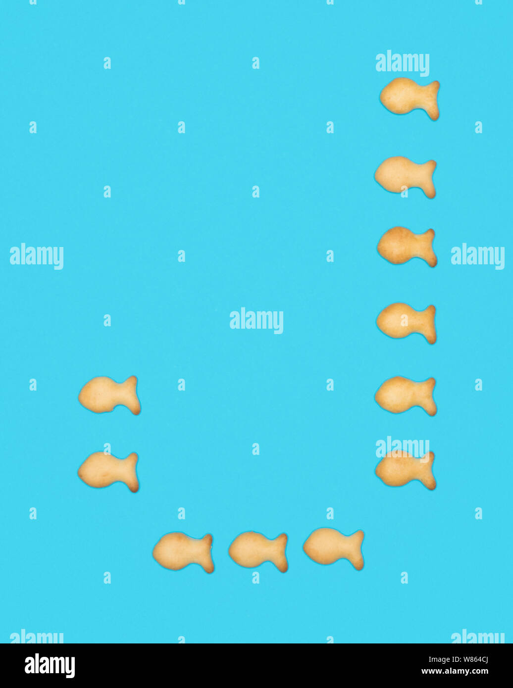 La lettre J'alphabet latin de cookies en forme de poisson sur fond bleu Banque D'Images