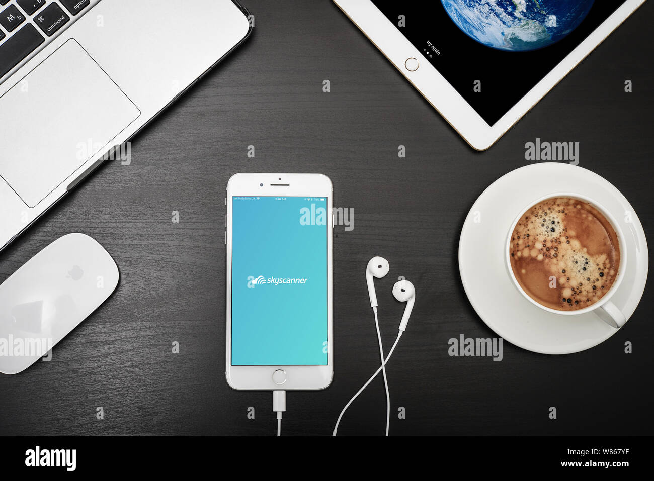 Kiev, Ukraine - Février 6, 2018 : Apple iPhone 8 plus avec Skyscanner app sur l'écran avec macbook, ipad, café et casque sur bureau noir, top v Banque D'Images