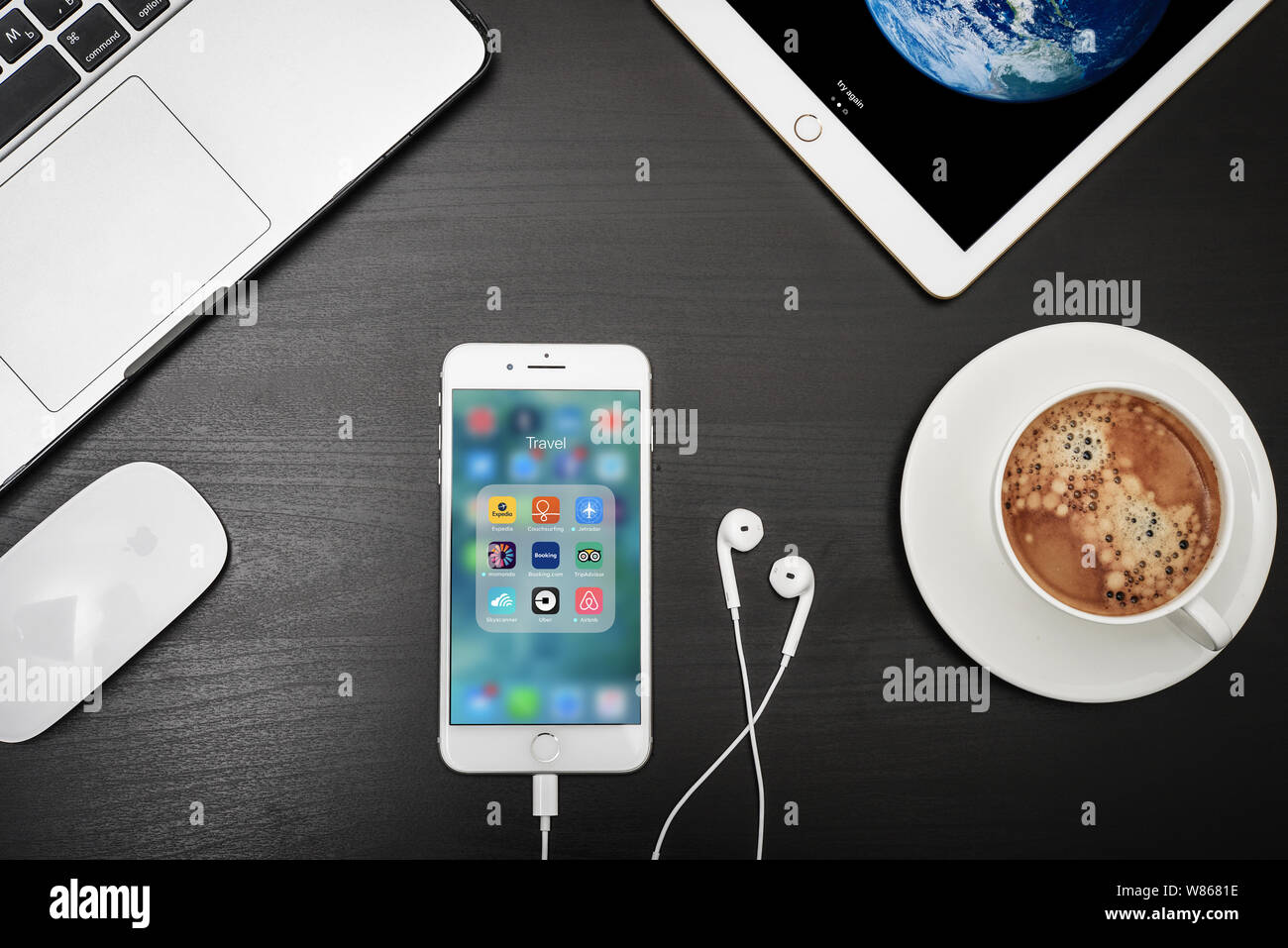 Kiev, Ukraine - Février 6, 2018 : Apple iPhone 8 plus avec applications de voyage sur l'écran avec macbook, ipad, café et casque sur bureau noir, vue du dessus Banque D'Images