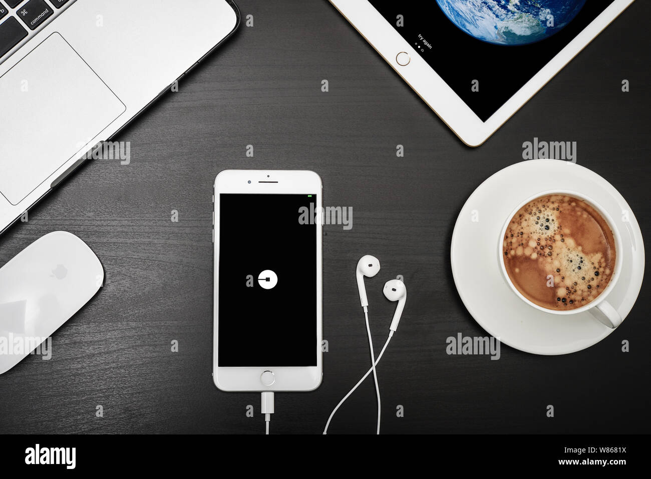 Kiev, Ukraine - Février 6, 2018 : Apple iPhone 8 plus avec Uber apps sur l'écran avec macbook, ipad, café et casque sur bureau noir, vue de dessus. Banque D'Images