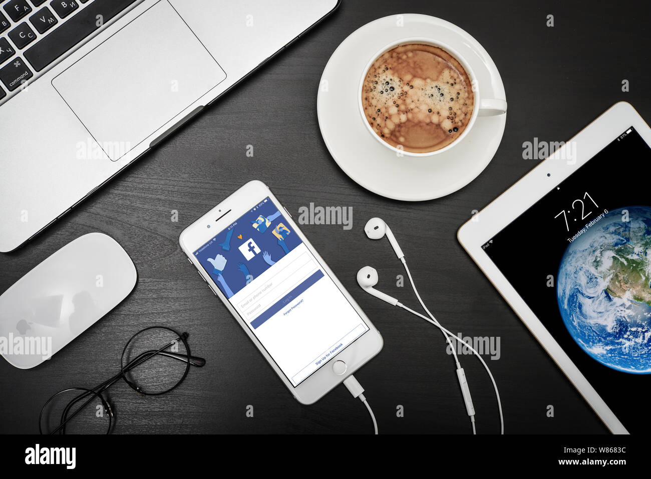 Kiev, Ukraine - Février 6, 2018 : Apple iPhone 8 plus avec Facebook app sur l'écran de bureau noir avec MacBook et du café, vue du dessus.Facebook est une façon Banque D'Images