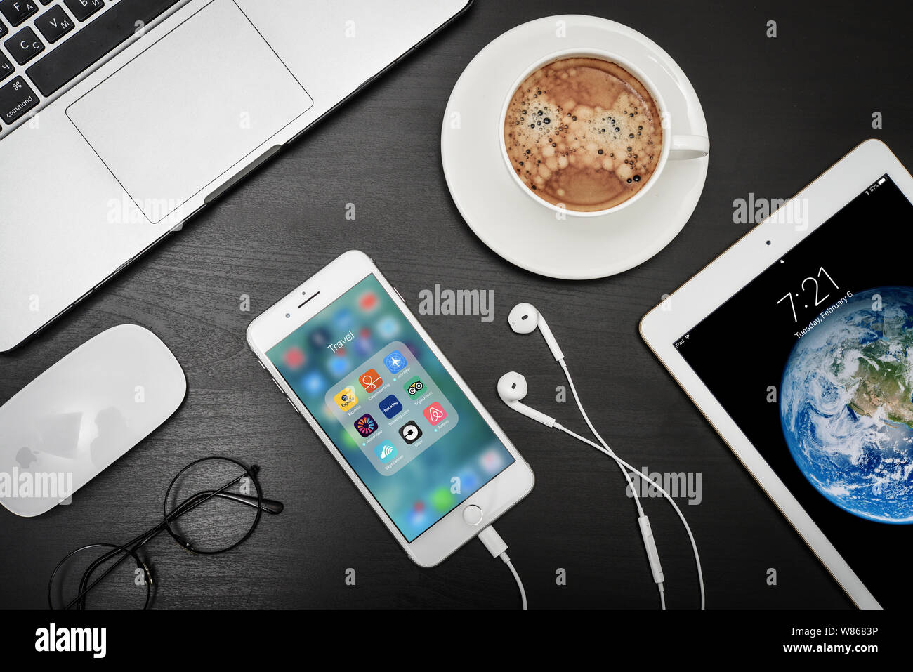 Kiev, Ukraine - Février 6, 2018 : Apple iPhone 8 plus avec applications de voyage sur l'écran avec macbook, ipad, café et casque sur bureau noir, vue du dessus Banque D'Images