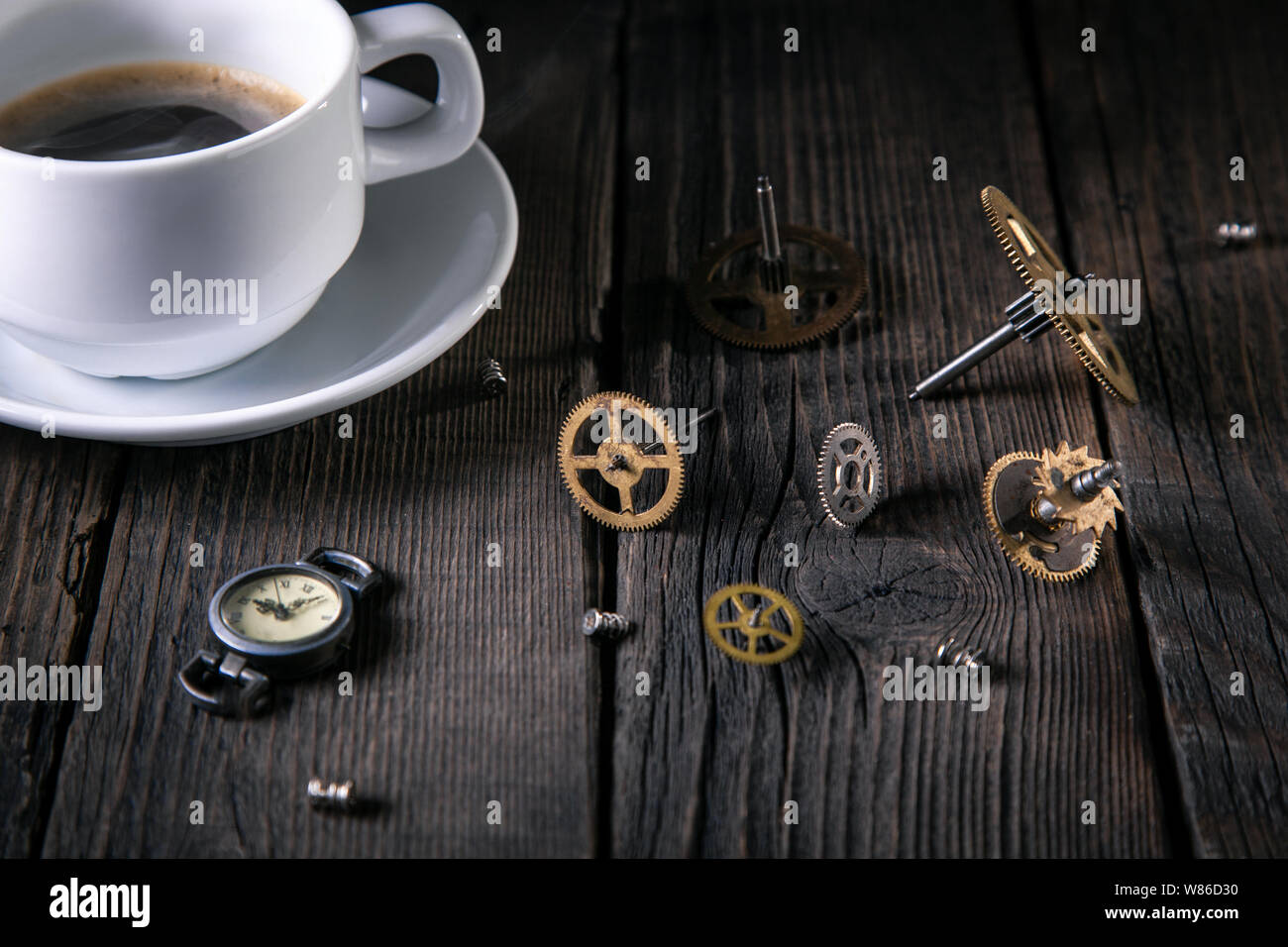 Montres Anciennes, clockwork - Engrenages, vis, une tasse de café non fini sur des planches. Bonne idée vintage, l'heure de l'intérieur. Banque D'Images