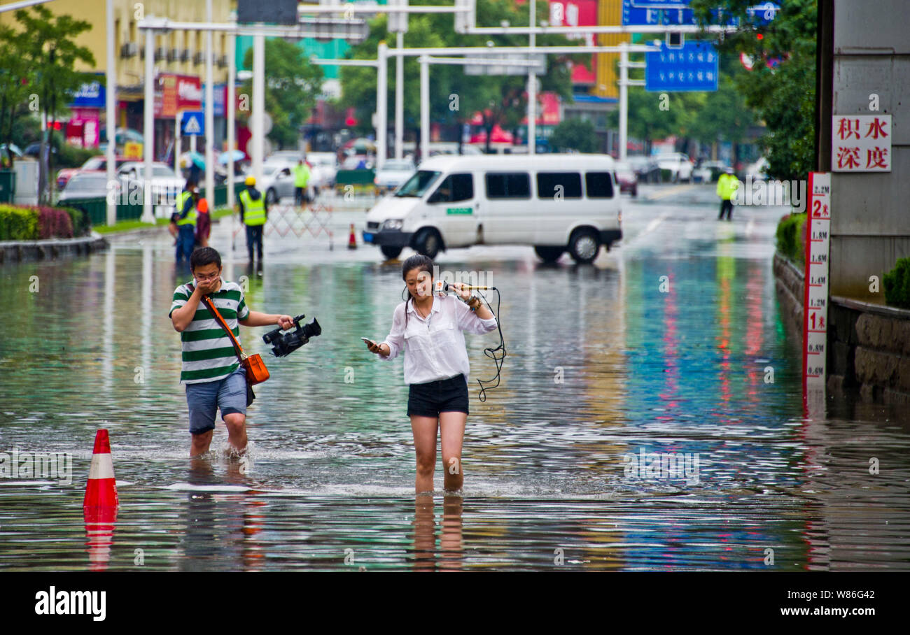 Les journalistes chinois à pied sur une route inondée causées par de fortes pluies à Zhenjiang city, Jiangsu province de Chine orientale, le 4 juillet 2016. Les inondations engendrées par torre Banque D'Images