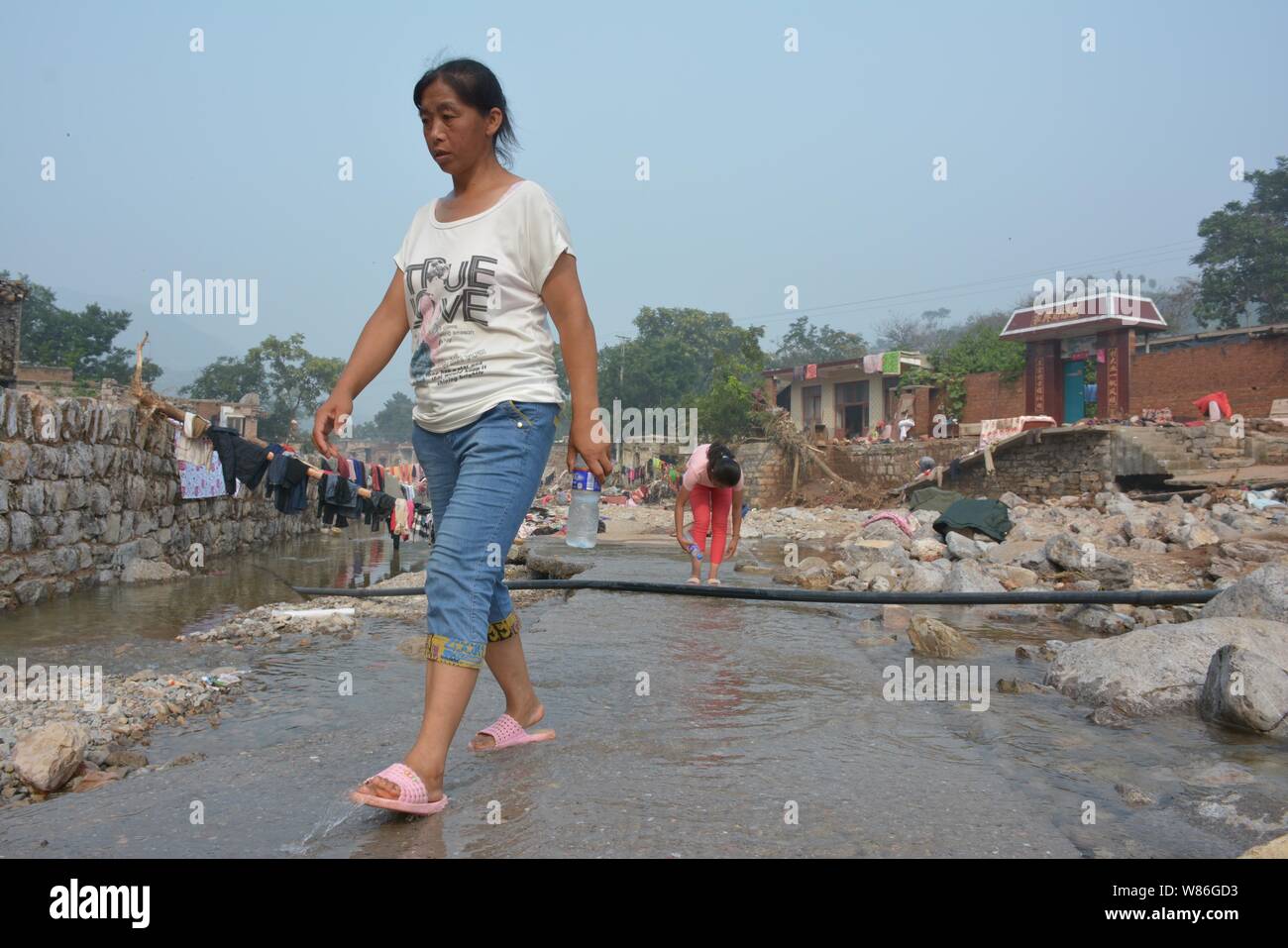 Les villageois locaux chinois passent devant les maisons dévastées par les inondations causées par de fortes pluies dans Taoquan, village du comté d'EC, Handan city, Hebei en Chine du nord pro Banque D'Images