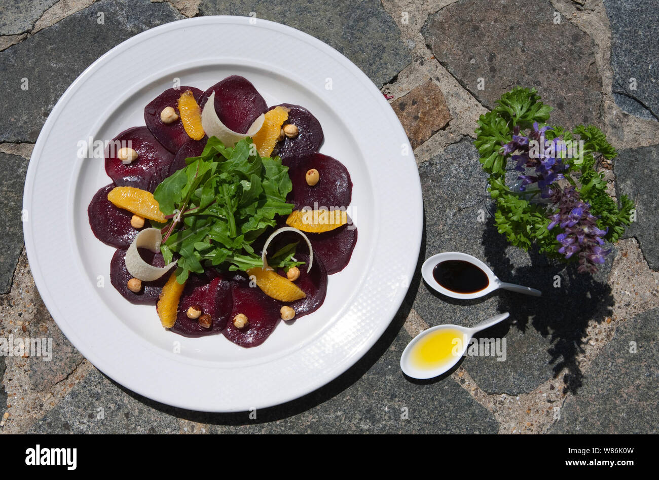 Salade de betterave et d'orange sur un pavage en pierre en arrière-plan avec l'huile d'olive et vinaigre de basalmic et garnir d'herbes Banque D'Images