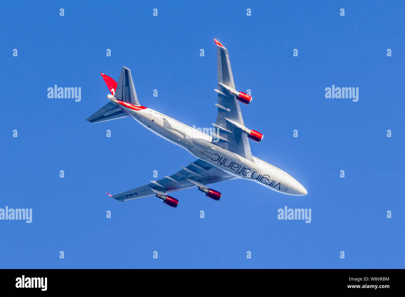 Jusqu'à la à la face inférieure d'un avion Virgin Atlantic, G-VXLG, un Boeing 747-41R aéronefs, de haut vol against blue sky au Royaume-Uni. Banque D'Images