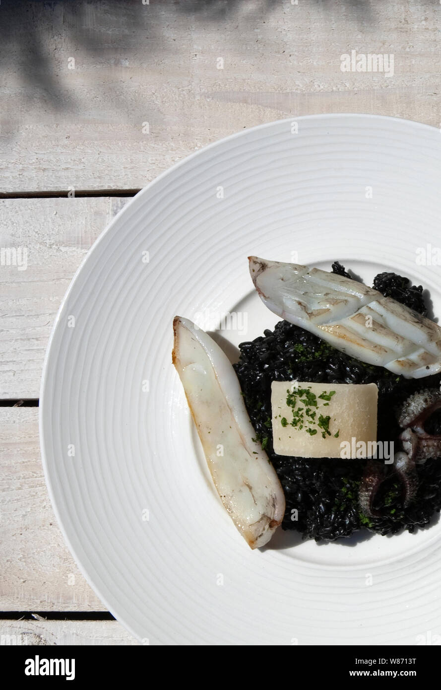 La seiche frais servis avec du riz fait à l'encre de seiche et un tourbillon de parmesan Banque D'Images