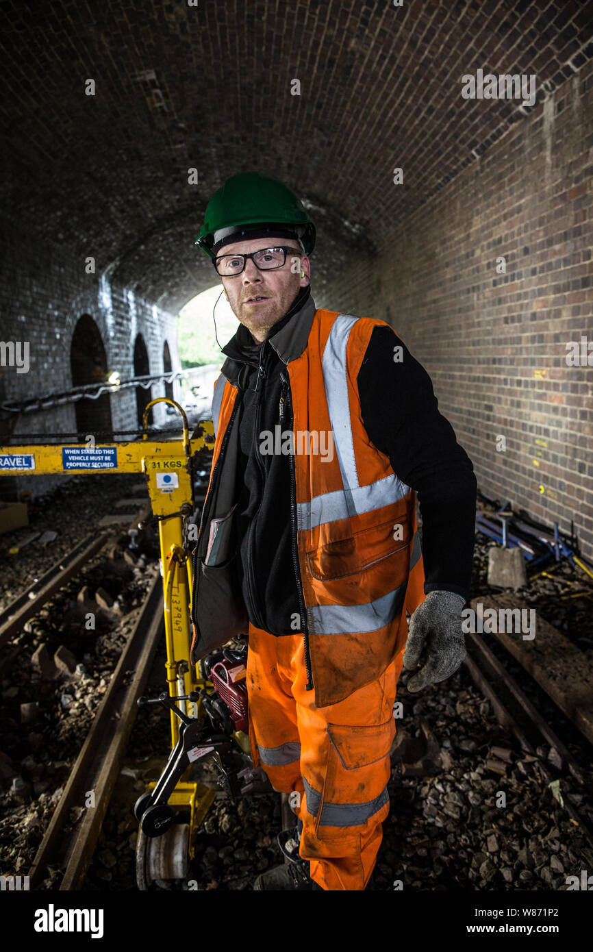 Le travail d'équipe de maintenance du métro de Londres sur la Central Line. Le broyage et le travail dégradé par les voies d'écrémage, bourrage et redistribuer le lest. London UK Banque D'Images