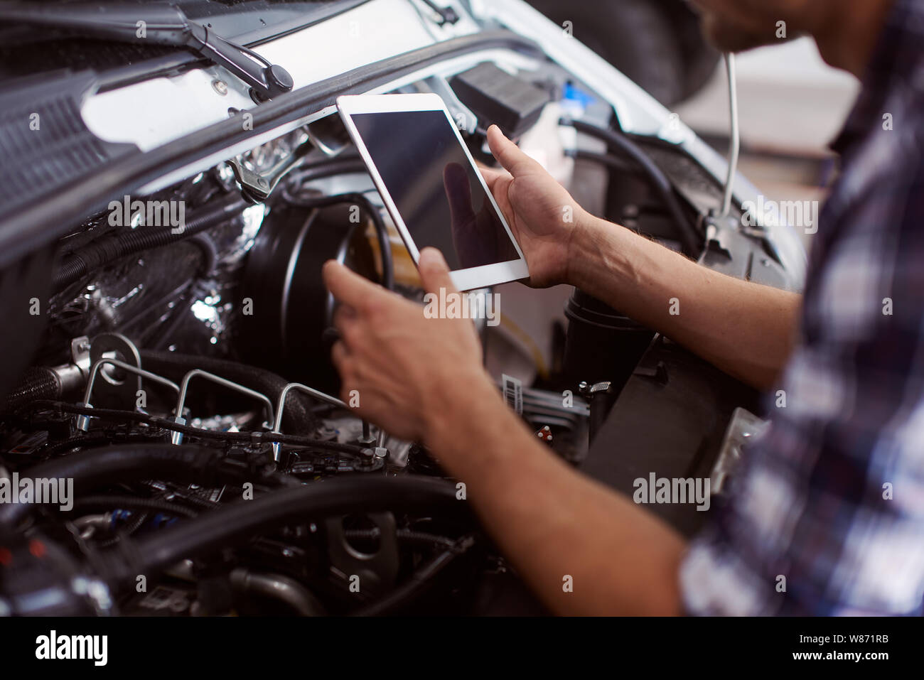 Close up of a man en utilisant sa tablette pour savoir comment régler le moteur de voiture. Banque D'Images