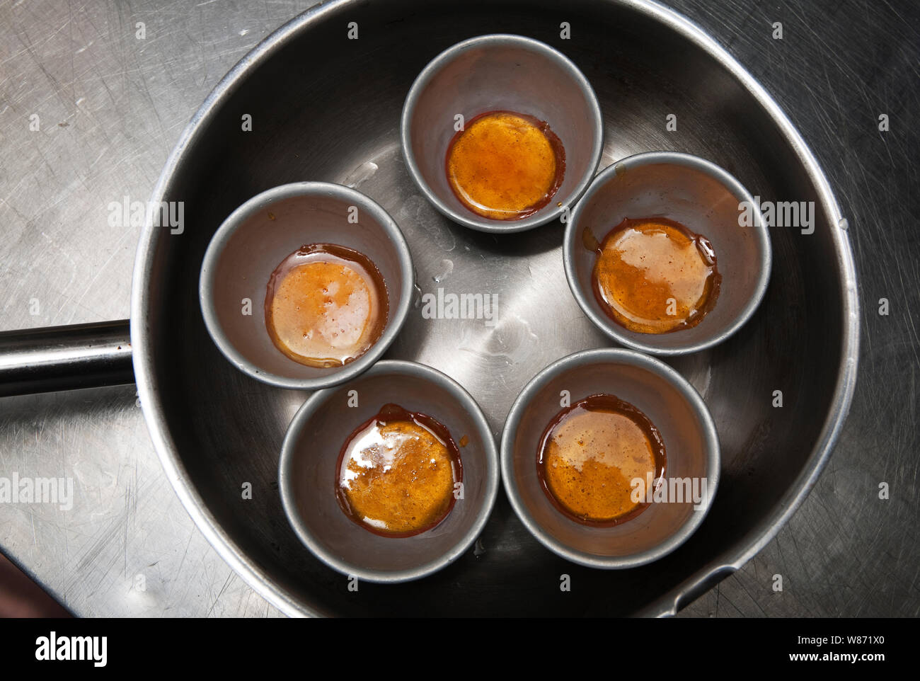 Garniture au caramel et mélanger pour crème caramel en production dans une cuisine professionnelle Banque D'Images