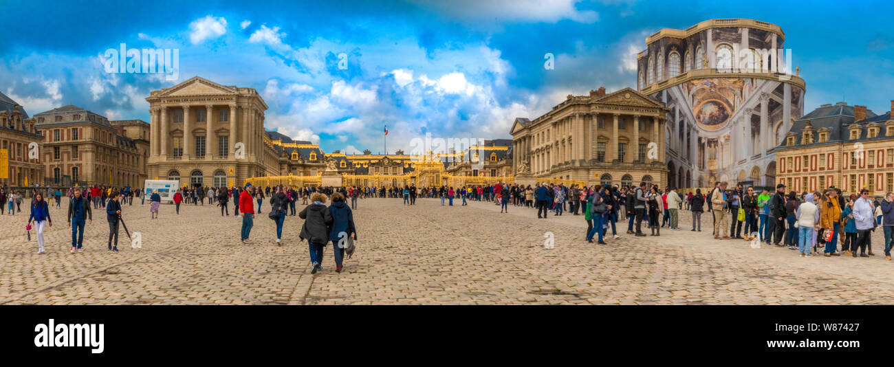 Grande image panoramique du célèbre château de Versailles près de la porte royale d'or où les visiteurs se pressent à l'entrée pavée dans le... Banque D'Images