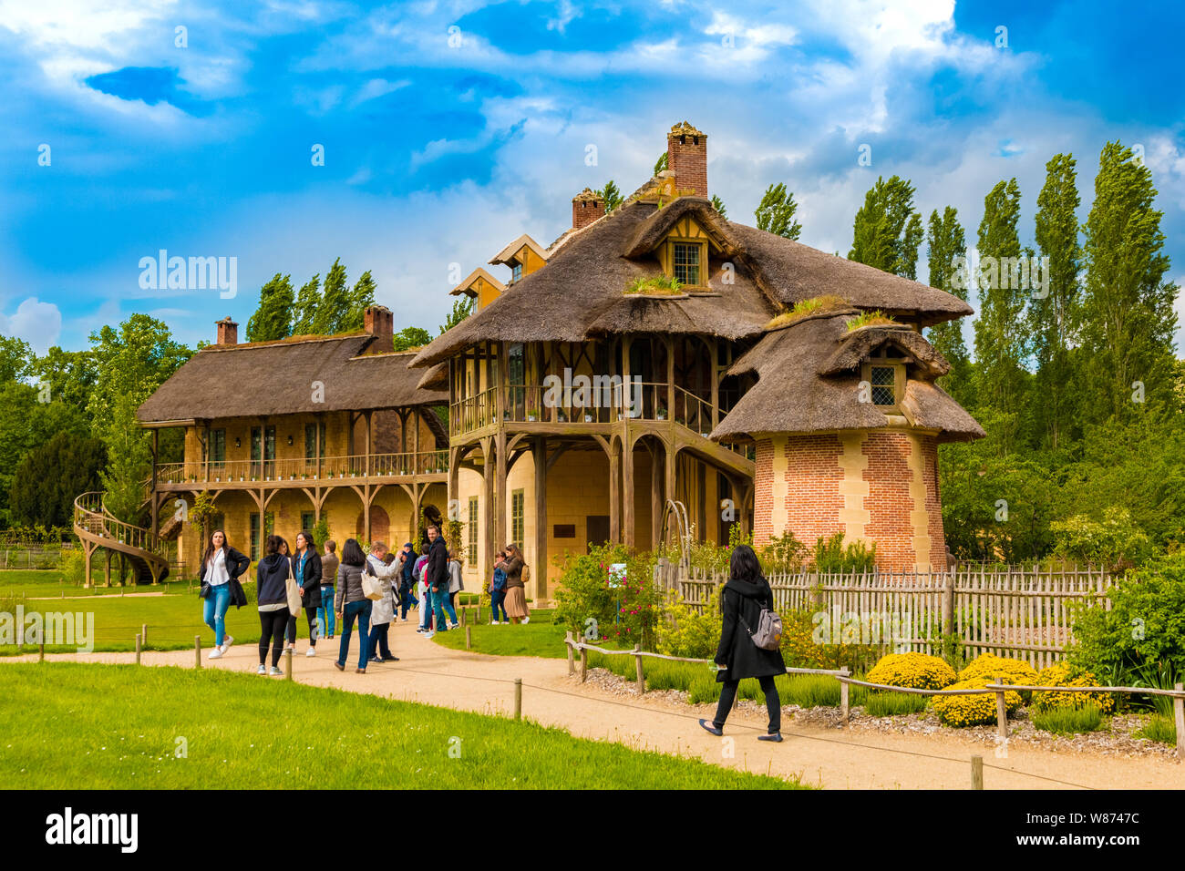 Les visiteurs d'admirer la maison de la Reine et d'une salle de billard dans le hameau du Trianon à Versailles Gardens. Les deux bâtiments rustiques sont reliés par un... Banque D'Images