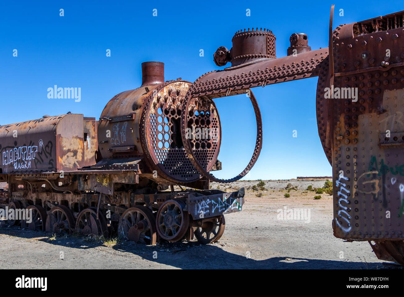 Cimetière de train, Uyuni, Bolivie : vieux abandonnés locomotives à vapeur, trains vintage se coucher sur le sol blanc et certains touristes dans un monument populaire Banque D'Images
