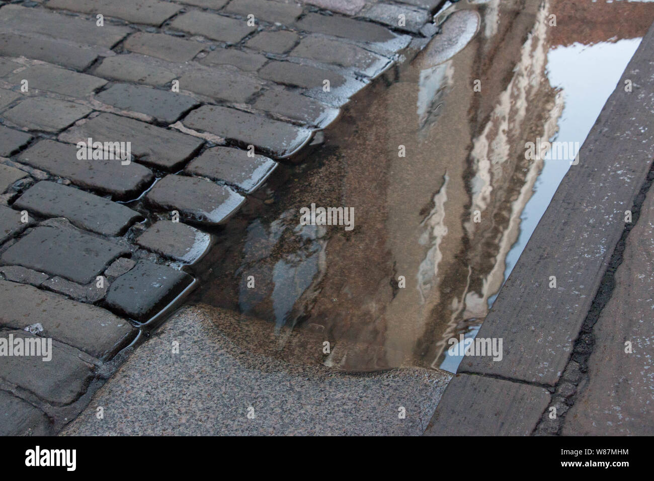 Reflet d'un édifice de style géorgien dans une flaque à côté de cobble stones Banque D'Images
