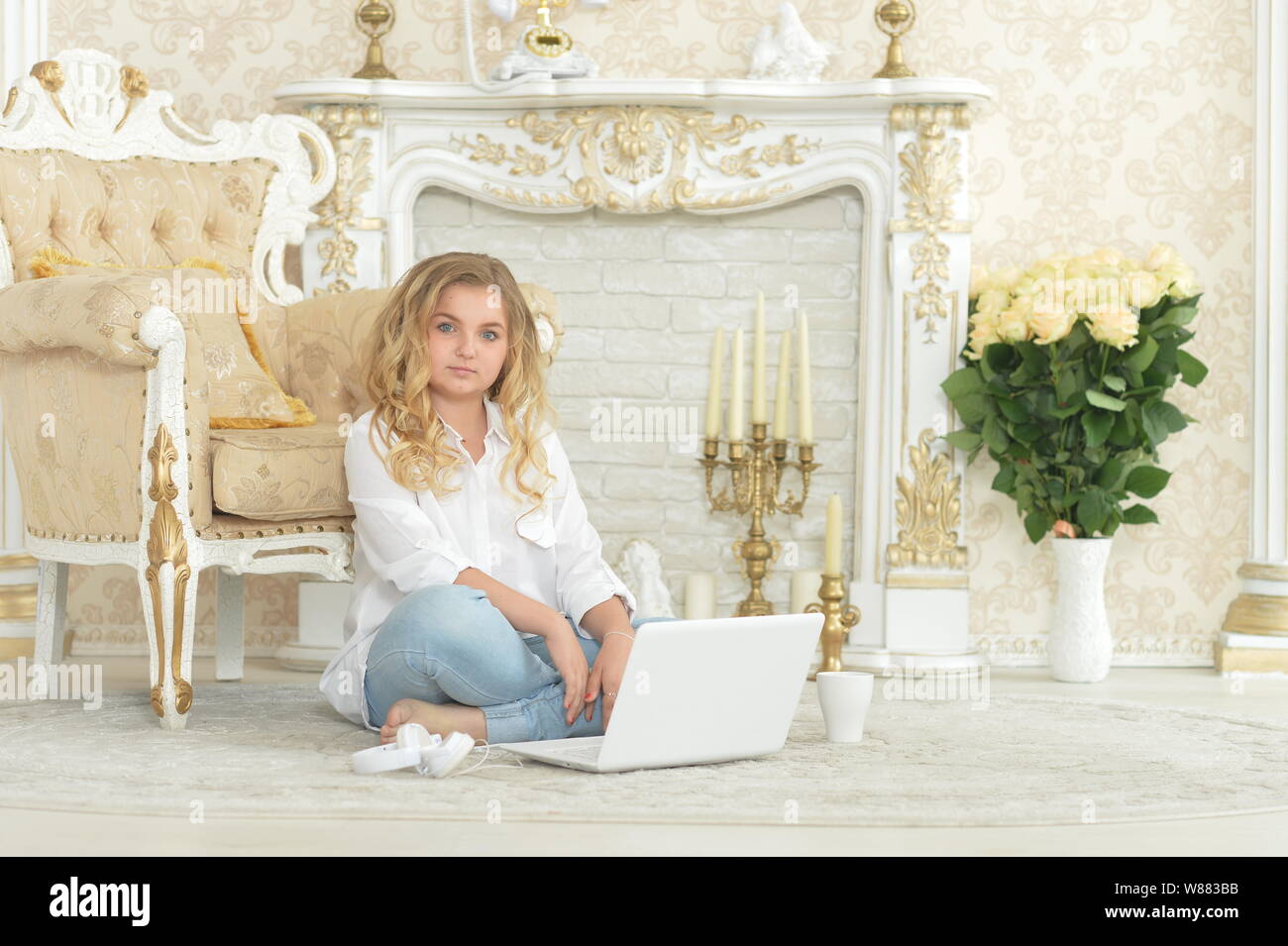 Curly blonde woman in casual clothing sitting on floor Banque D'Images