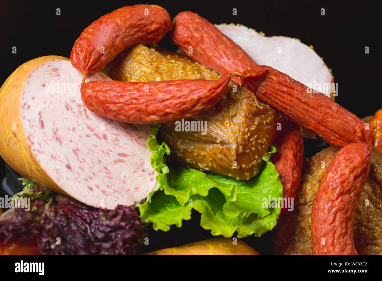 Différents types de saucisses et produits de viande sur un fond noir. Banque D'Images