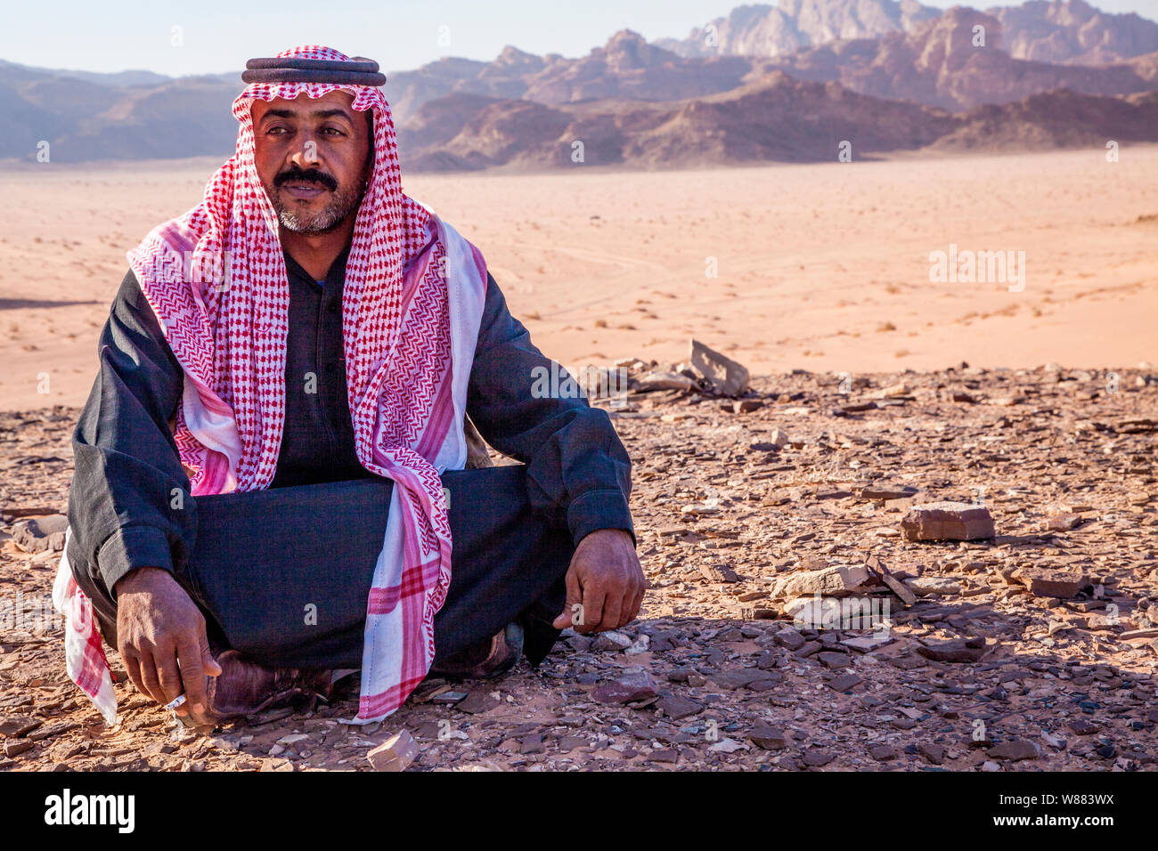 Un bédouin homme est assis sur un fond du désert de Jordanie à Wadi Rum ou la vallée de la Lune Banque D'Images