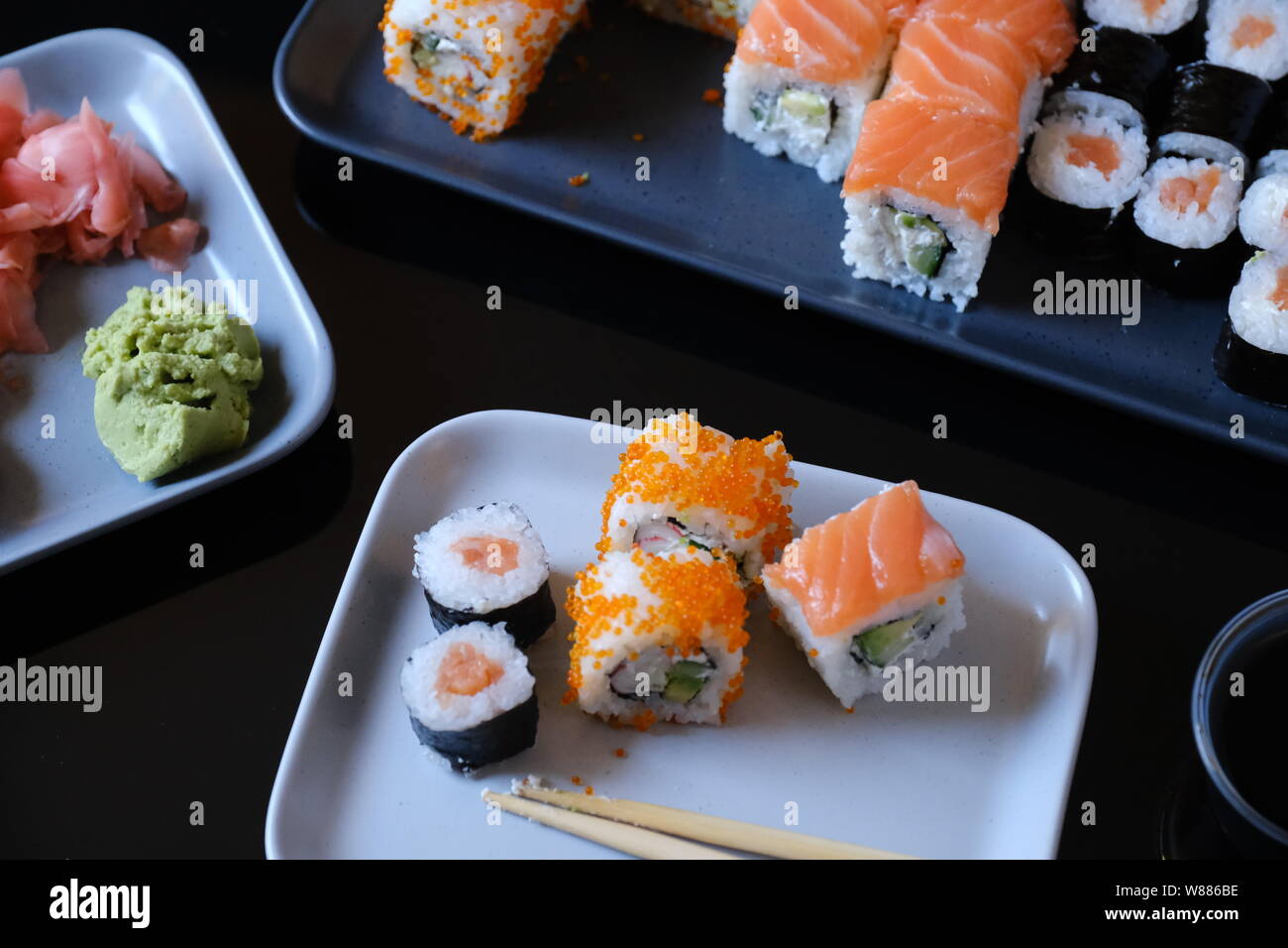 Sushi roll avec des fruits de mer et la sauce soja, le wasabi et le gingembre. Rouleau de sushi au saumon et caviar de poisson volant sur un tableau noir. Banque D'Images