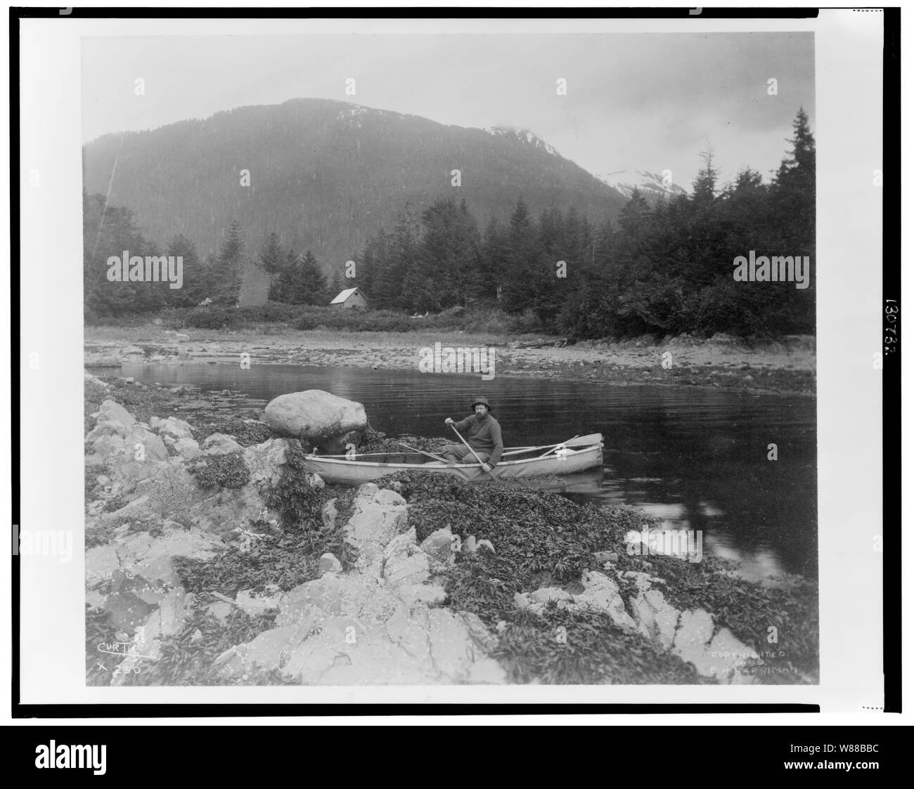 Un homme, peut-être Lewis Morris Rutherford, assis dans un canot sur une rivière en Alaska, 1899 / Curtis Banque D'Images