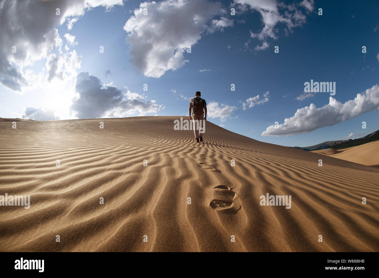 Un homme seul marche dans les dunes du désert sur Banque D'Images